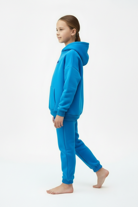 Child wearing a blue hoodie and pants on a white background
