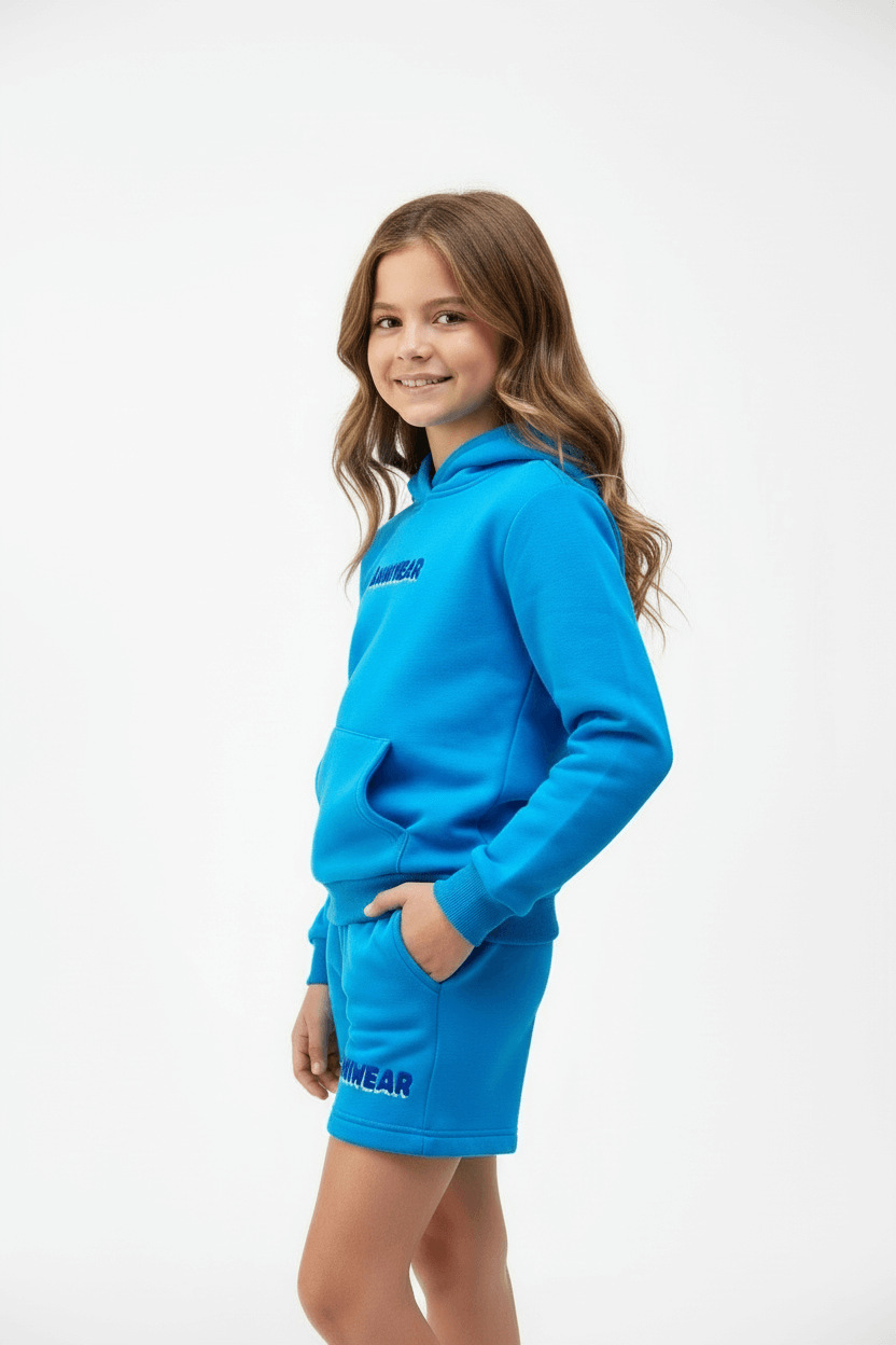 Young girl wearing a blue hoodie and shorts set on a white background