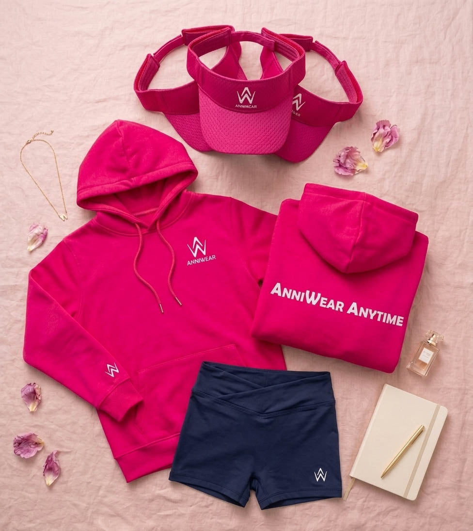 flat lay of a fuchsia pink visor, navy blue shorts, and a jagger hoodie on a pink background