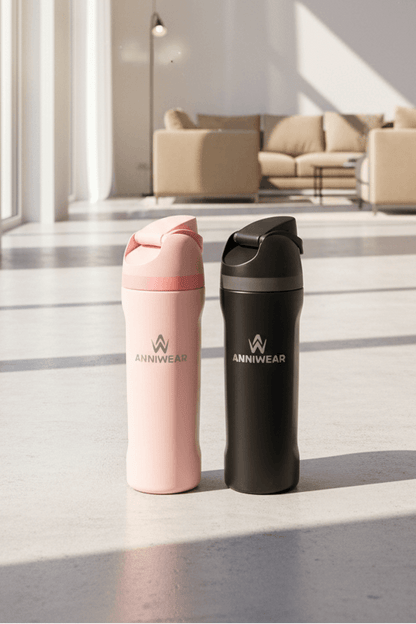 Two insulated water bottles, one pink and one black, with 'ANIIWEAR' branding, on a light wooden floor.