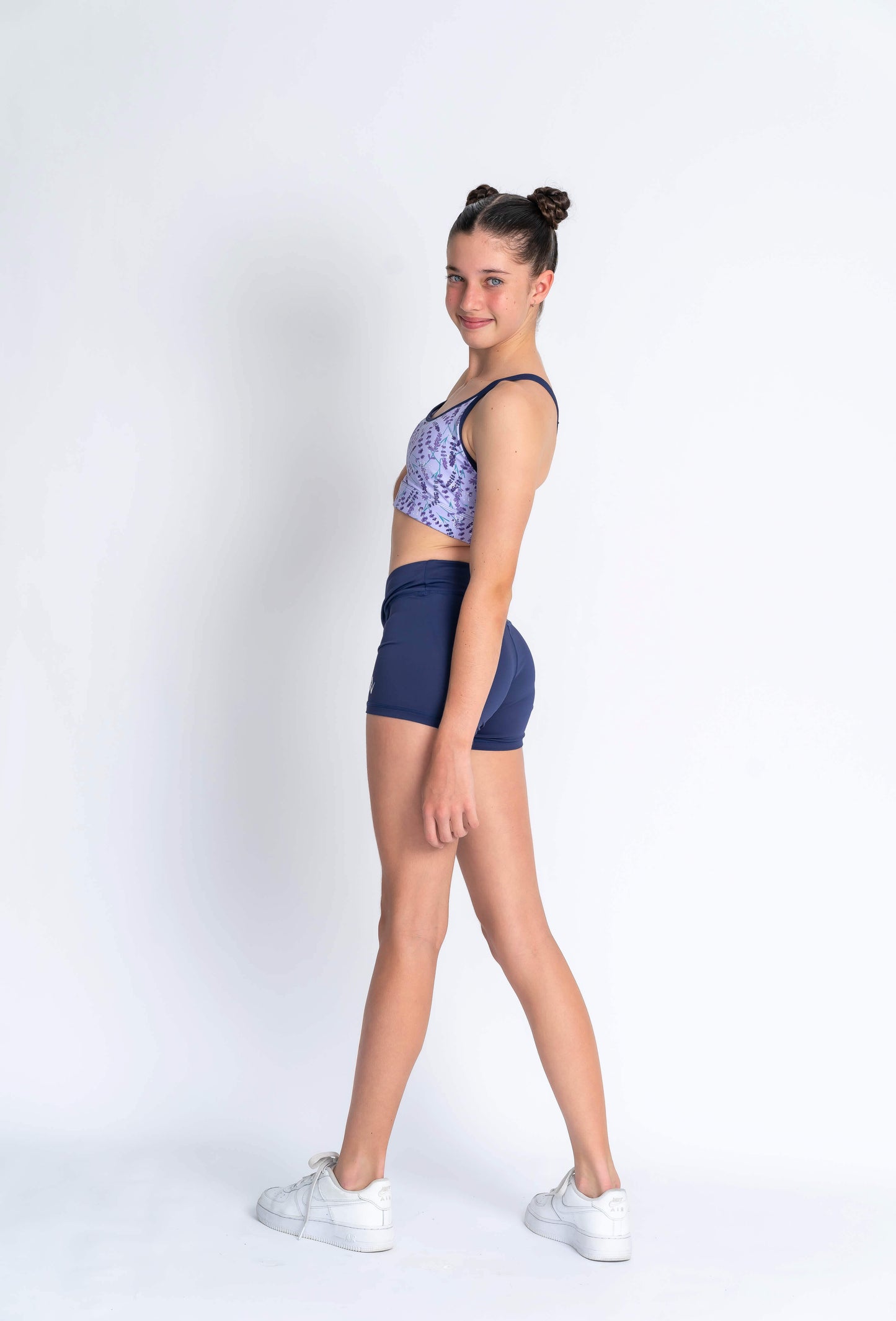 A female model wearing a lavender haze crop top with a patterned design, paired with navy blue shorts,