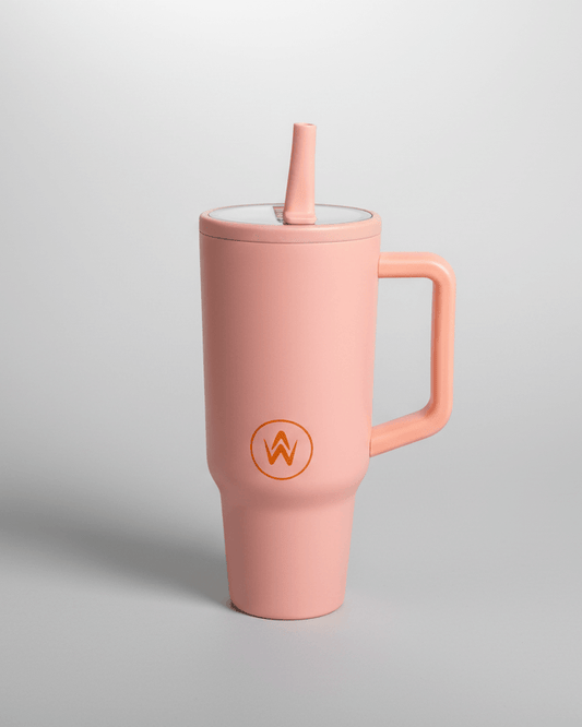 Peach tumbler with straw and handle on a light gray background