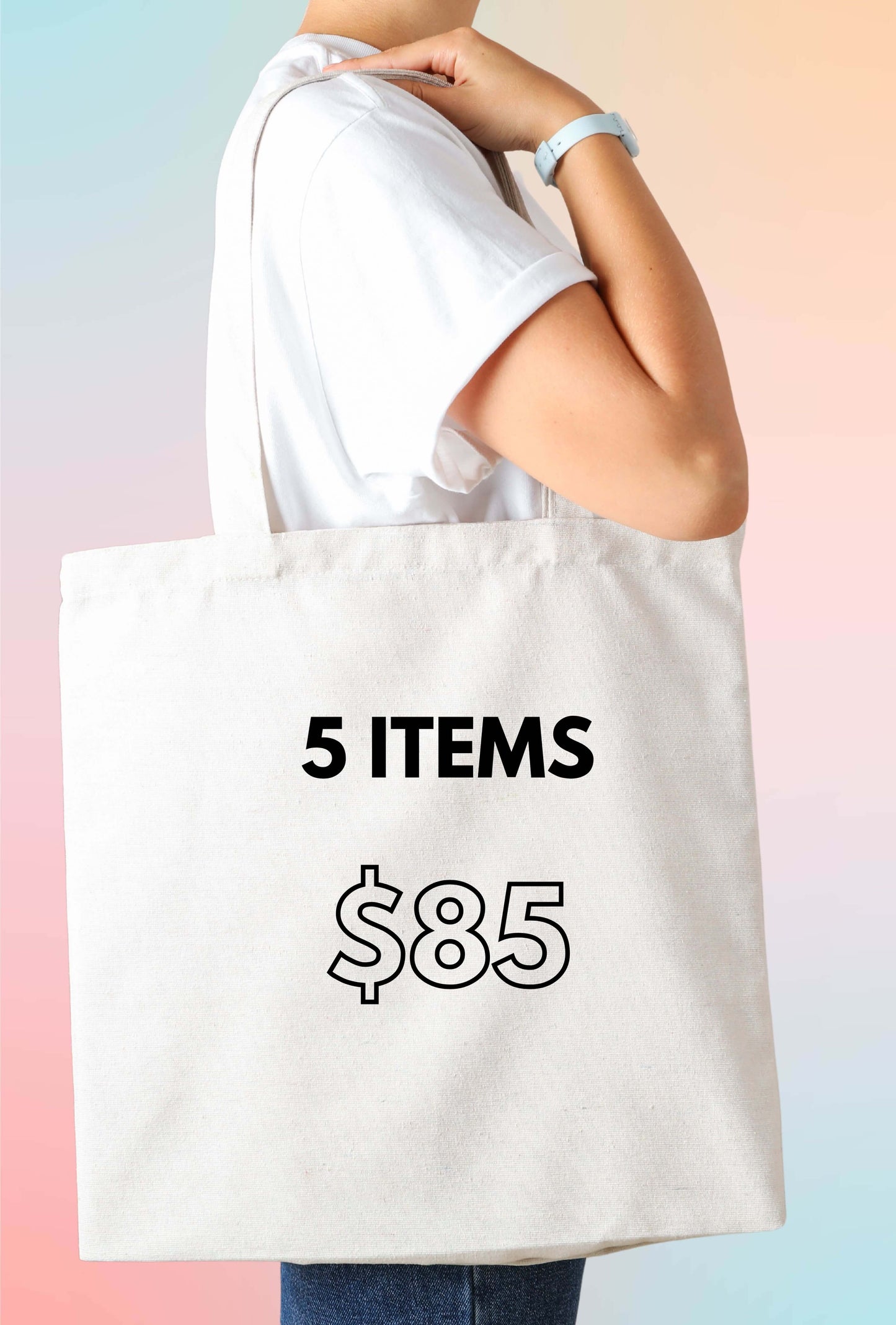 A person holding a white cotton tote bag with '5 ITEMS $85' printed on it, indicating the contents are yet to be discovered.