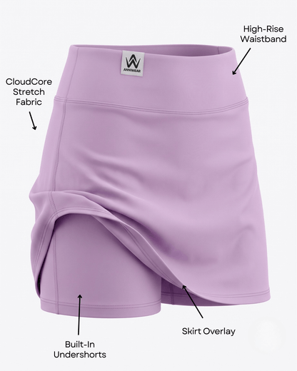 A lavender athletic skirt with overlaid shorts and multiple callout labels pointing to features like the high-rise waistband, CloudCore stretch fabric, built-in undershorts, and skirt overlay, on a light gray background.