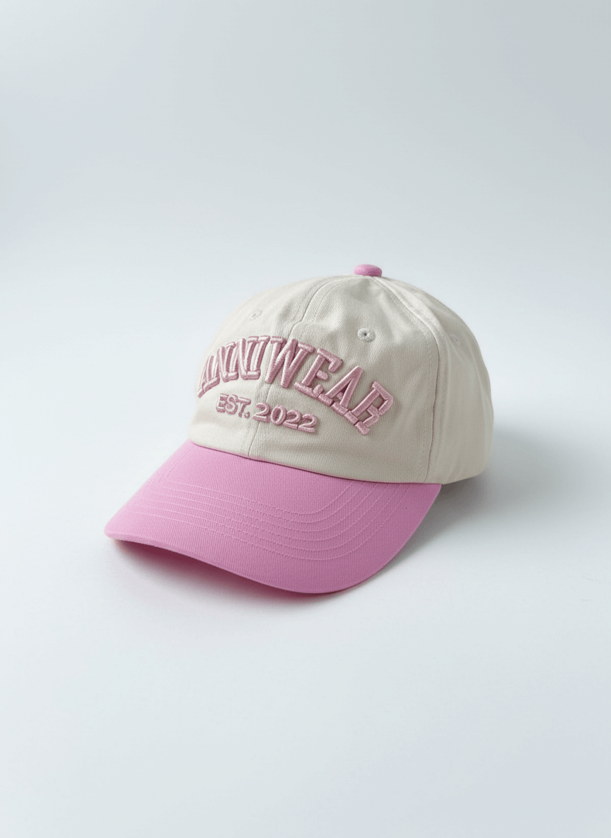 Beige and pink cap with embroidered text on a light gray background