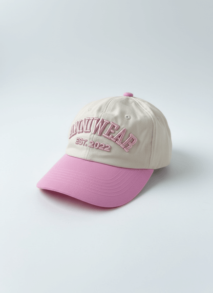 Beige and pink cap with embroidered text on a light gray background