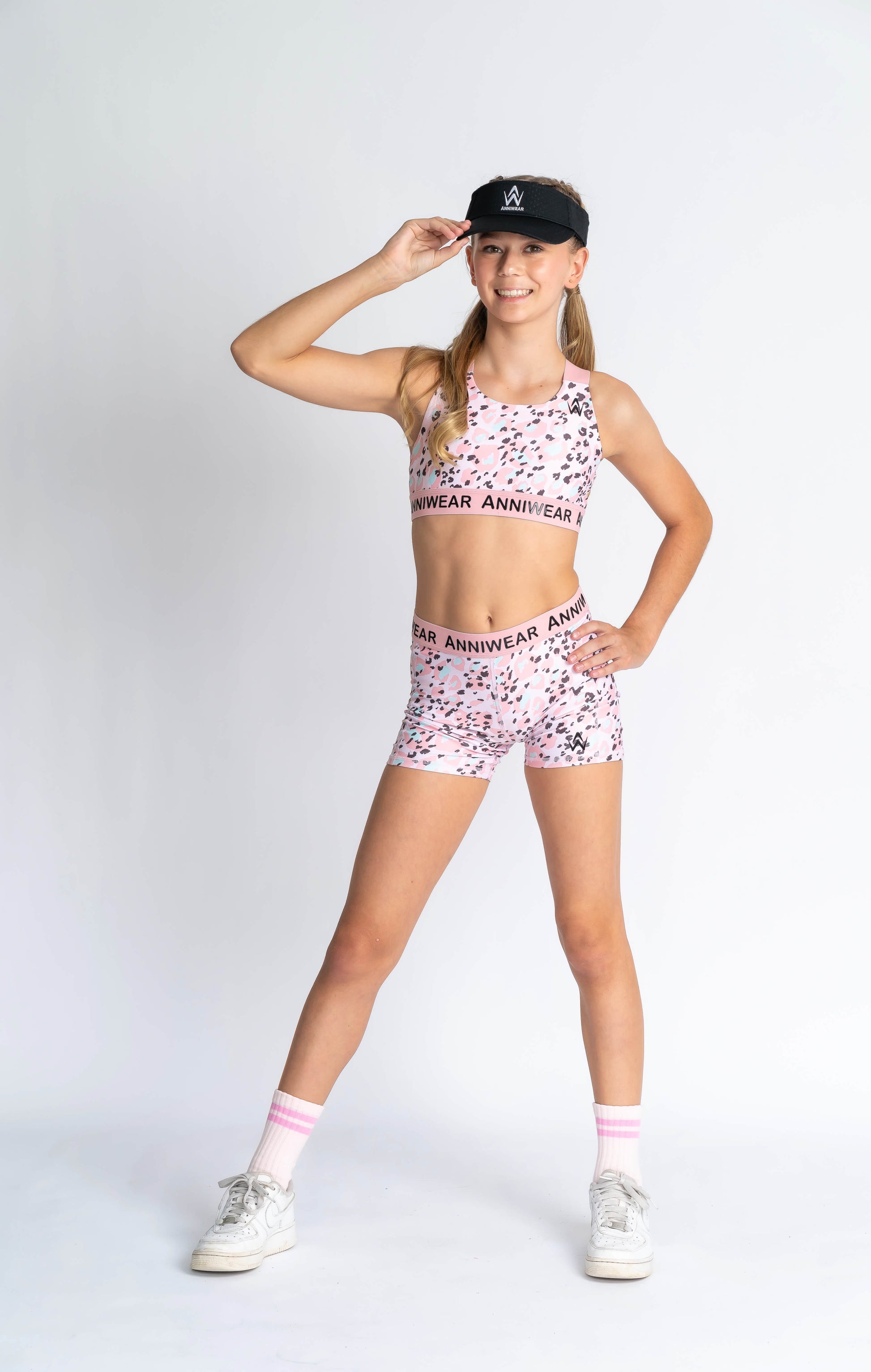 A female model wearing a pink animal print crop top and matching shorts, standing against a plain background.