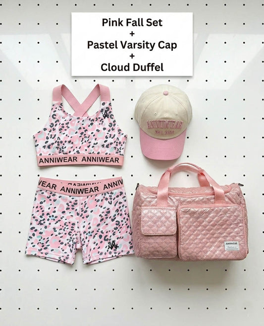 Pink athletic set, cap, and duffel bag on a white pegboard background