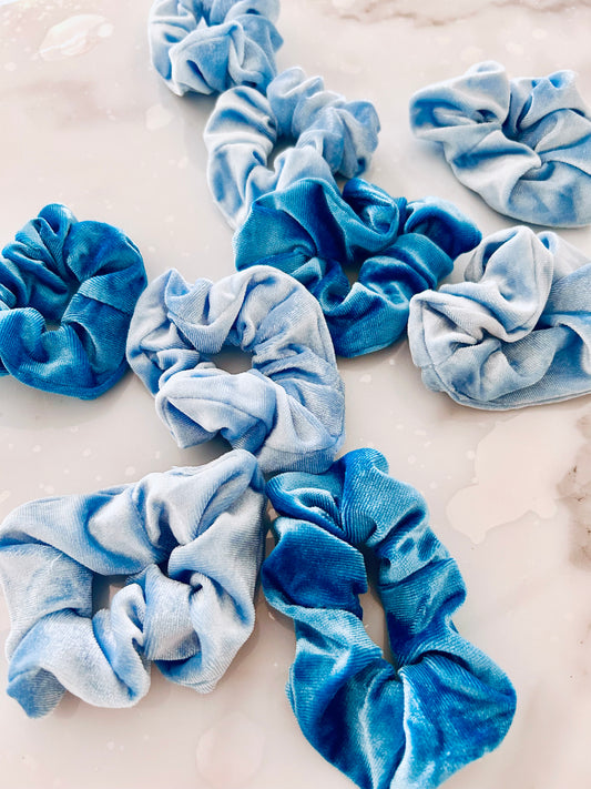 A collection of blue coloured scrunchies displayed on a marble surface.