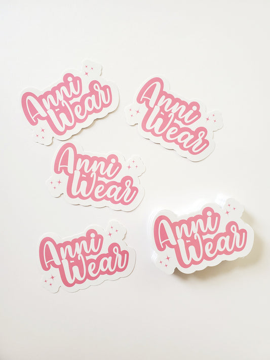 Die cut waterproof vinyl stickers with the text 'Anni Wear' in pink color, surrounded by small pink dots.