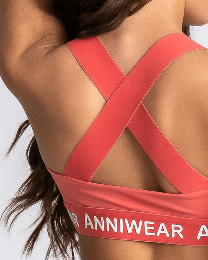 Coral sports bra with 'Anniwear' branding on a plain background
