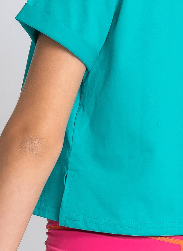 Close-up of a teal cropped t shirt with rolled sleeves with a neutral background