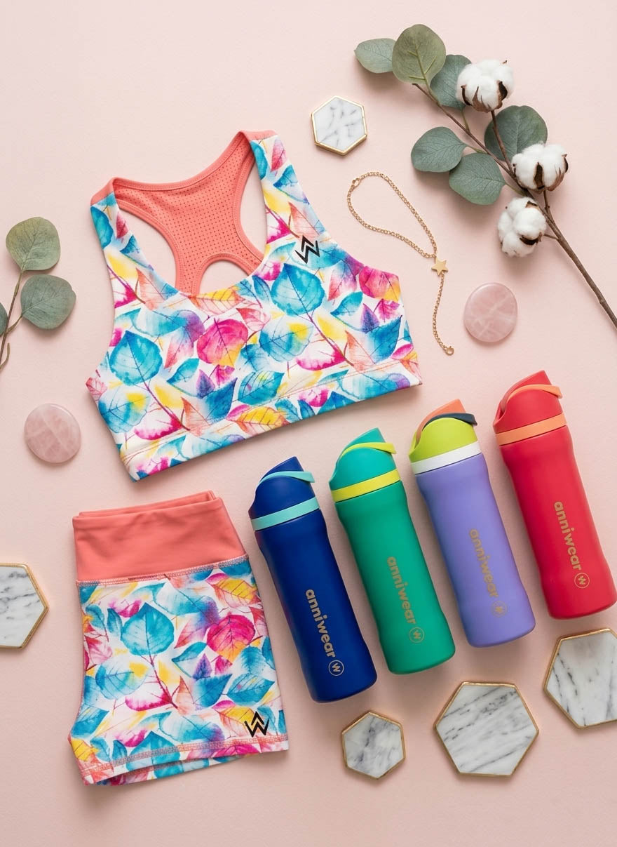 Colorful sports crop top and leggings set with water bottles on a pink background