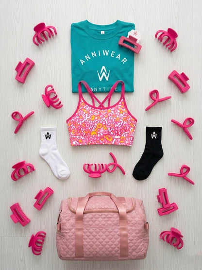 flat lay design of the tee, crop, shorts, socks, hair clip and a duffel bag.