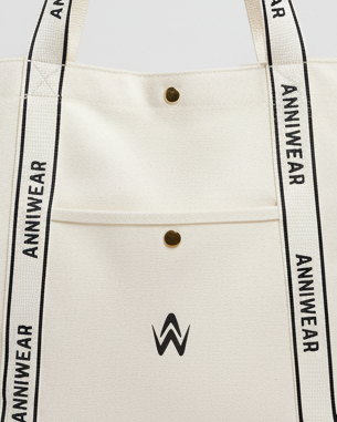 Close-up of a beige tote bag with 'ANNIWEAR' branding and a logo.
