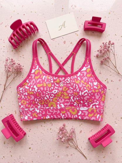 Pink sports crop top with animal print surrounded by pink hair accessories on a light background