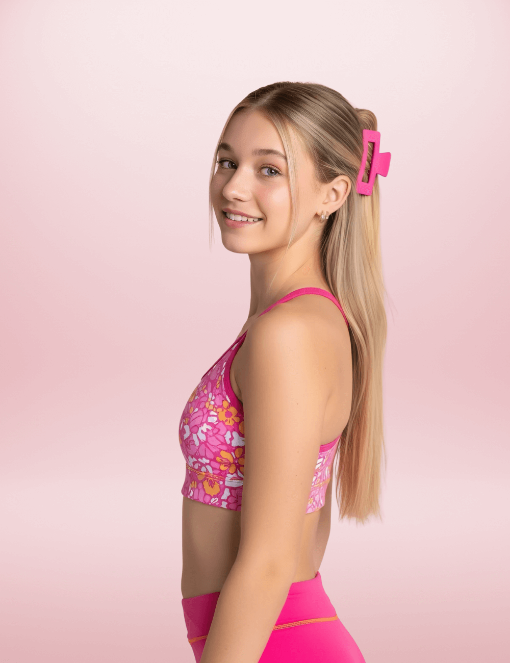 Girl wearing a pink sports bra and malibu short with a wild animal pattern crop on a pink background