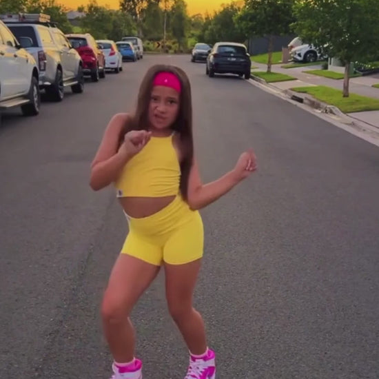 girl dancing while wearing a yellow activewear set on the road